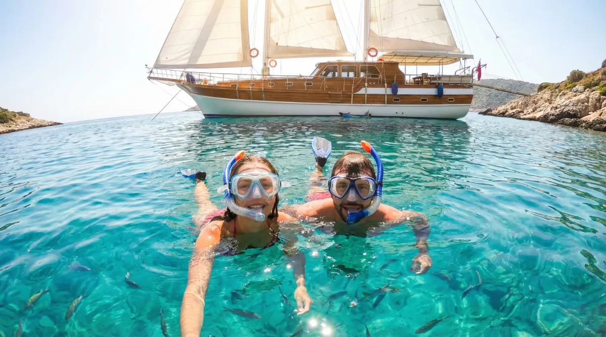 Couple snorkeling in crystal clear water near anchored gulet at Orak Island Turkey